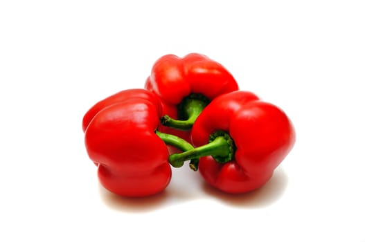 three red fresh paprikas isolated on the white
