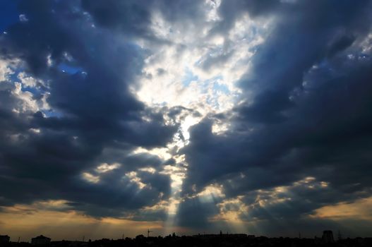 Dark clouds and little peace of blue sky with sunlight under the town