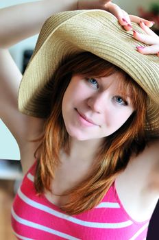 pretty redheaded girl is  wearing straw hat