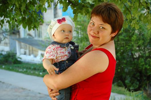 Amazed little girl and her mother on nature background (trees branchlets).