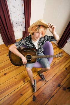 Young musician with an old guitar in an empty room