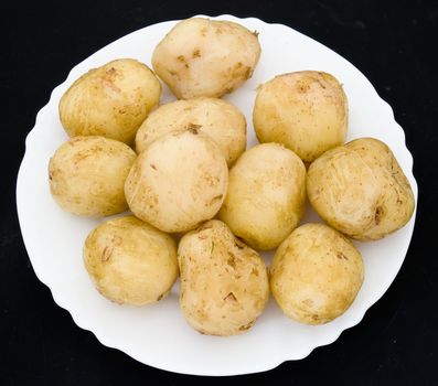 Potatoes on a white plate on a black background