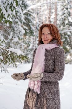 Happy red-haired woman having fun on winters day in forest.