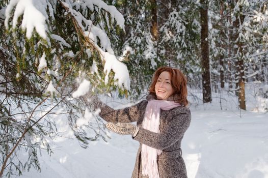 Happy red-haired woman having fun on winters day in forest.