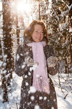 Happy red-haired woman having fun on winters day in forest.