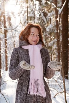 Happy red-haired woman having fun on winters day in forest.