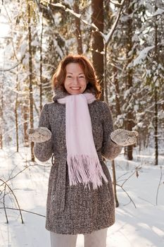 Happy red-haired woman having fun on winters day in forest.