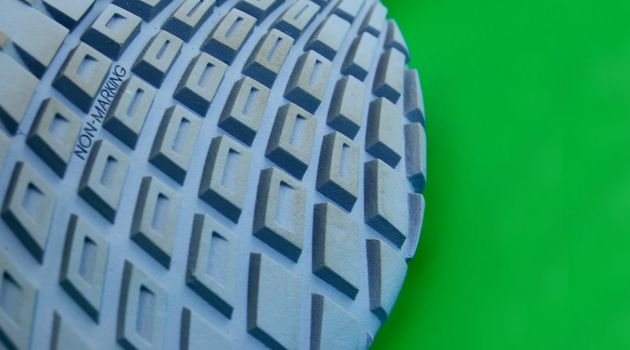 macro pattern of rubber sole of sneakers against green