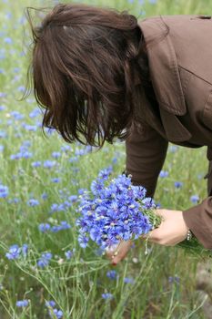 Foung woman collectong flowers on the meadow