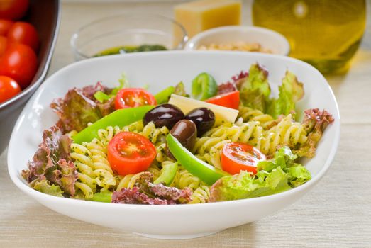 fresh healthy homemade italian fusilli pasta salad with parmesan cheese,pachino cherry tomatoes, black olives and mix vegetables ,dressed with extra-virgin olive oil and pesto sauce