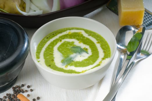 fresh spinach soup on a white bowl with sage and cream on top