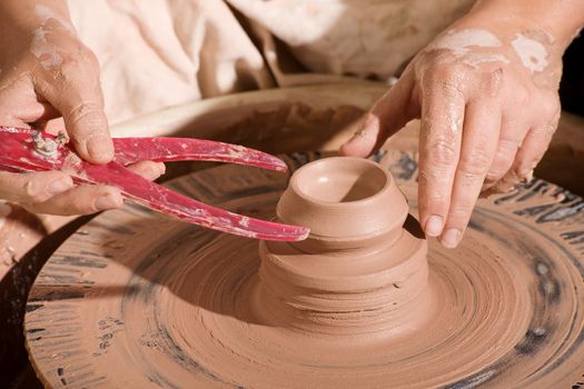 Potter using calipers to measure fresh clay pot