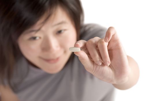 Woman with pill on white background, focus on pill.