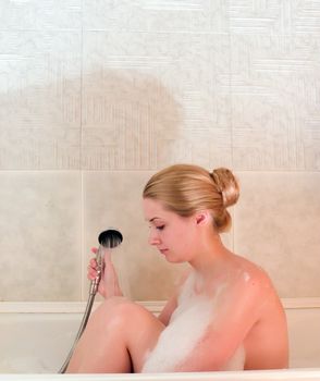 young beautiful girl in a bath with shower