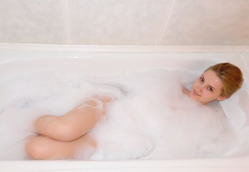 young beautiful girl in a bath with shower