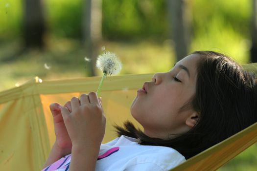 Little girl blowing on a dandelion