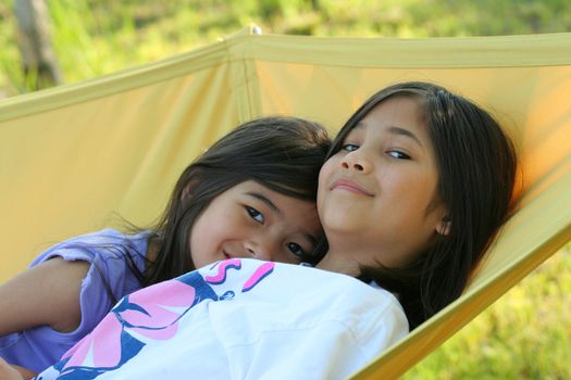 Two girls swinging on a hammock