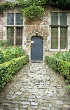 A cobblestone path leads to the doorway of an Abbey in Leuven, Belgium.