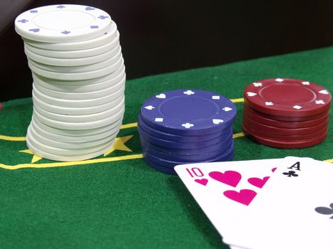 Stack of poker chips next to two playing cards on a poker table