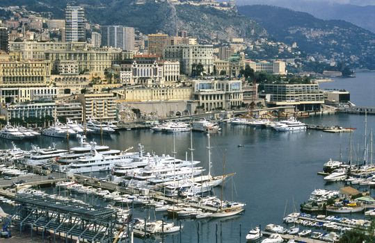 Luxury yachts dock in Monaco, home of the Monaco Grand Prix and the Monte Carlo Casino visible in the background.