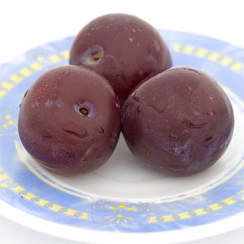 Three plums on a saucer close up