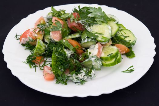 salad on a white plate on a black background