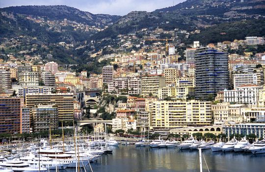 Luxury yachts dock in Monaco as condominiums nestle the mountainside.