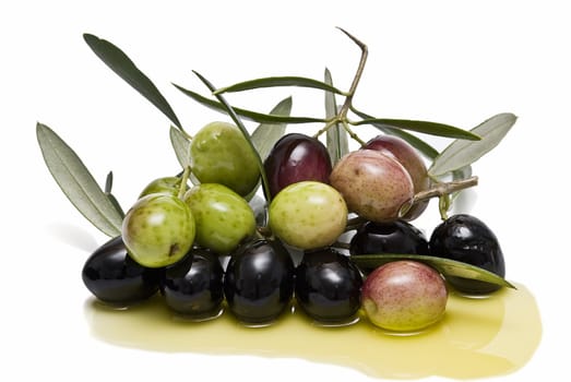 Some olives with branches and leaves and some olive oil.