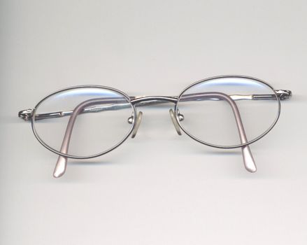 metal rim spectacles over a grey background