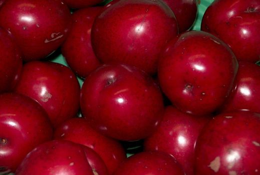 background of firm red delicious plums closeup
