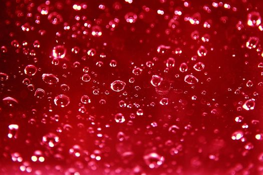 sparkling rain drops on glass against a red background