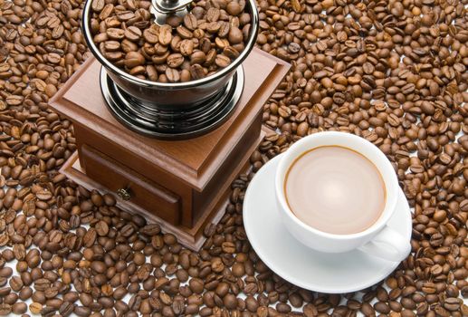 Old coffee grinder and a cup of coffee