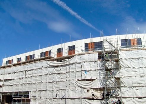 A general view of the exterior of a new modern building site development covered in scaffolding and cladding.