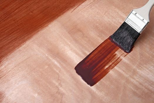 Paintbrush and fresh paint on wooden surface.