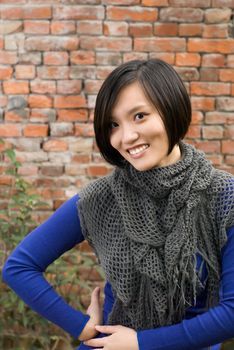Modern woman of Asian smile against old brick wall.