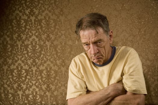 Senior Man Against a Gold Background with a Stern Expression and Arms Crossed