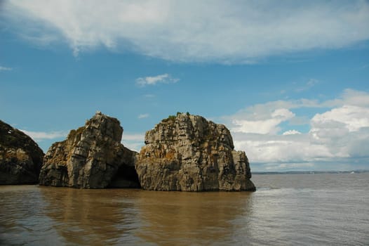 rocks of Flat holm island in wales with blues sky covered by clouds and sea