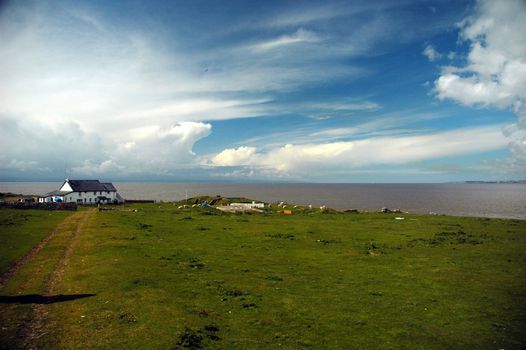 sheep famr on Flat holm island with grass field and beautiful blue sky with wild white clouds