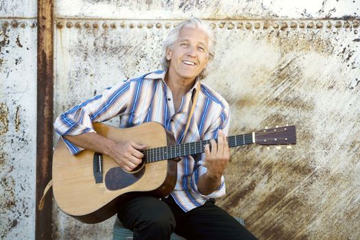 Handsome man playing an old acoustic guitar