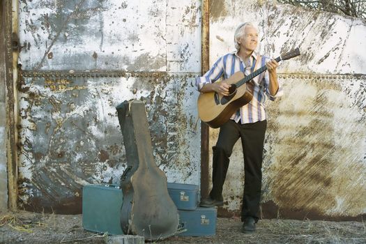 Handsome man playing an old acoustic guitar