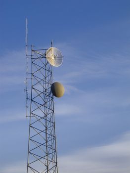 small telecommunications mast with blue sky and white clouds in background