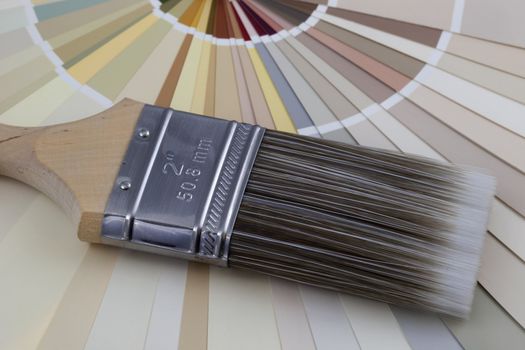 nylon paintbrush against radiating paint color swatches (pastel earth tones)