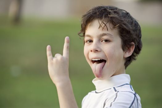 Boy sticking out his tongue and making a bull horn gesture with his hand