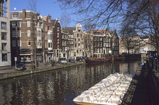 A row of canal bikes, or peddal boats, await tourists on a canal in Amsterdam.