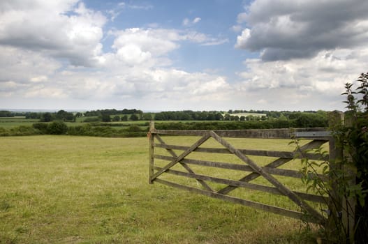 An open farm gate leading to a field