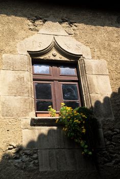An ornate window with yellow flowers in the morning sun and shadow, Barcelona, Spain
