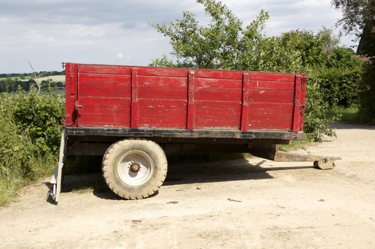 A red farm trailer in a farm yard