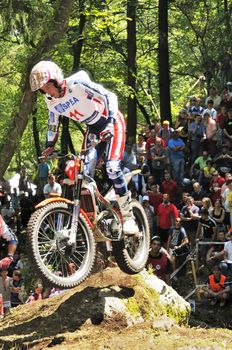 Trial rider jumping and spectators in background 