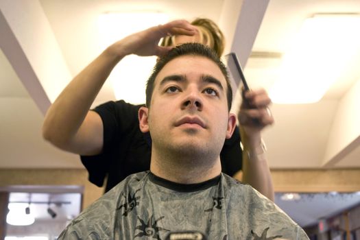 A young man getting his hair cut by a hairdresser at the salon