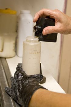 A hairdresser mixing a hair color formula in the back room.